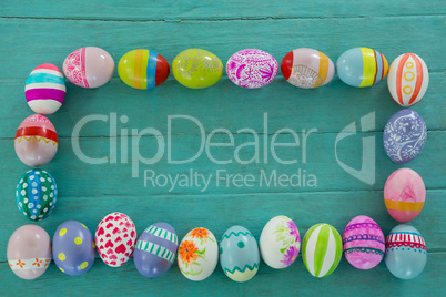 Painted Easter eggs arranged in rectangle shape on wooden plank
