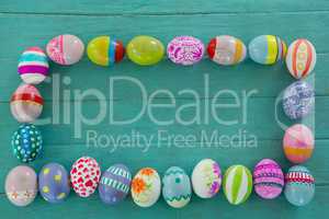 Painted Easter eggs arranged in rectangle shape on wooden plank