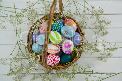 Basket with painted Easter eggs on wooden background