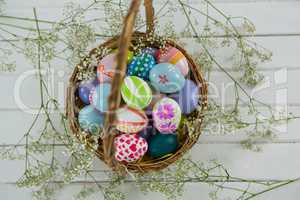 Basket with painted Easter eggs on wooden background