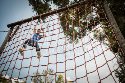 Woman climbing a net during obstacle course