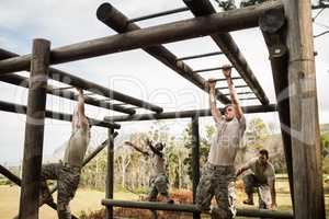 Soldiers climbing monkey bars