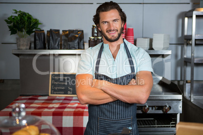 Portrait of smiling male staff standing with arms crossed