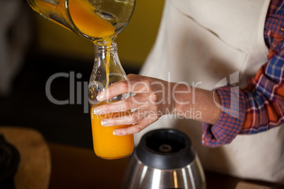 Female staff pouring juice in a bottle