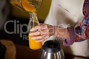 Female staff pouring juice in a bottle