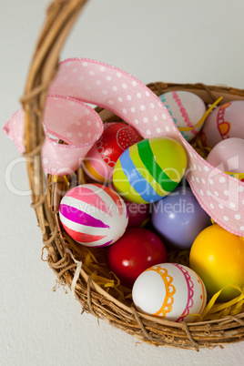 Various Easter eggs with ribbon in wicker basket