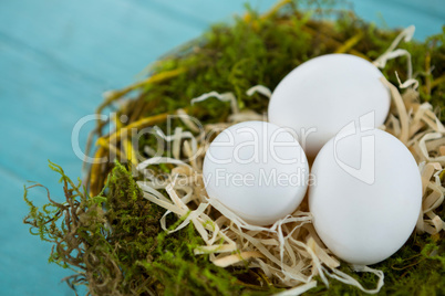 White eggs in the nest on wooden surface