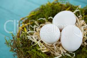 White eggs in the nest on wooden surface