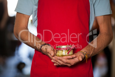 Shop assistant holding a jar of pickle in grocery shop