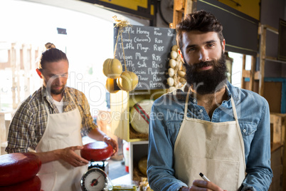 Salesman writing on clipboard at counter in grocery shop