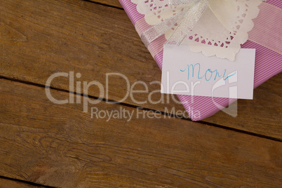 Gift box with mom text on card against wooden background