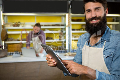 Portrait of smiling staff using digital tablet