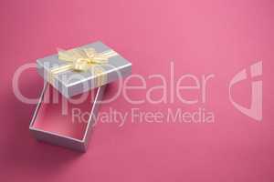 Open gift box against pink background