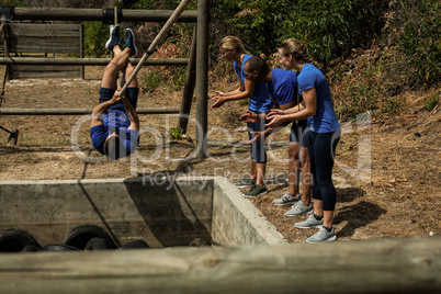 Man crossing the rope during obstacle course while people cheering him