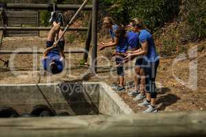 Man crossing the rope during obstacle course while people cheering him