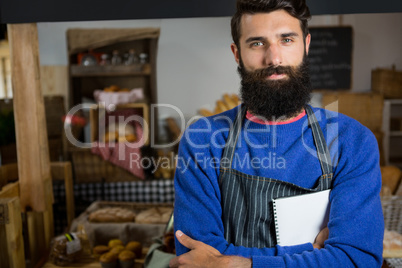 Portrait of male staff standing with arms crossed at counter