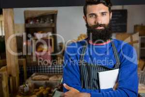 Portrait of male staff standing with arms crossed at counter