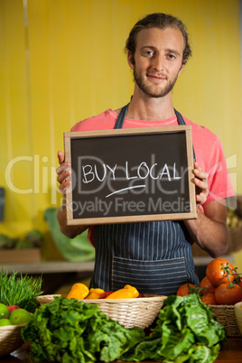 Portrait of male staff holding slate board in organic section