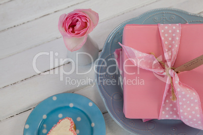 Gift box, flower vase and cookie on wooden surface