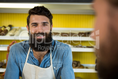 Smiling male staff standing at meat shop