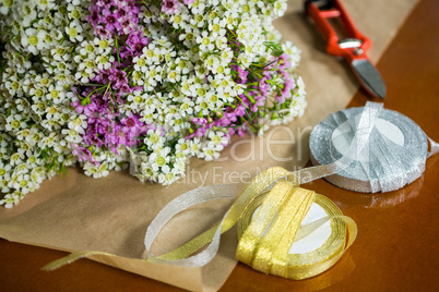 Flowers with ribbons on the wooden worktop at flower shop