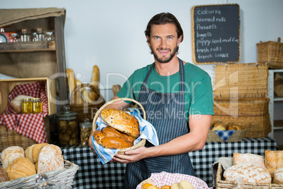 Portrait of male staff holding a basket of bread