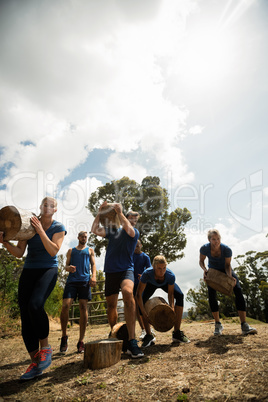 People lifting heavy wooden logs during obstacle course