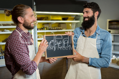 Smiling male staffs holding a open sign