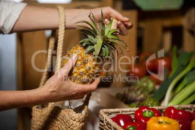 Woman buying pineapple at organic section