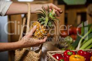 Woman buying pineapple at organic section