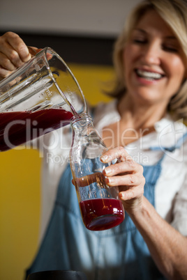 Female staff pouring juice in a bottle