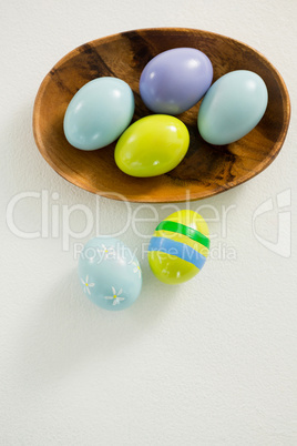 Colorful Easter eggs in bowl with two painted Easter eggs