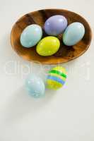 Colorful Easter eggs in bowl with two painted Easter eggs