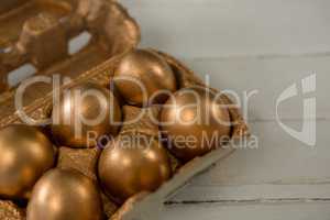 Close-up of golden Easter eggs in the carton