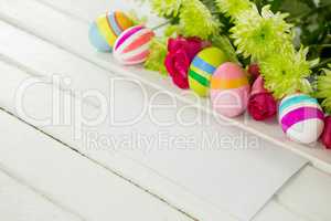 Painted Easter eggs, bunch of flower and envelope on wooden background