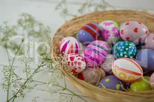 Basket with painted Easter eggs on wooden background