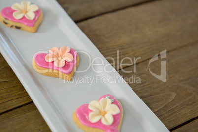 Heart shape cookies in tray on wooden plank