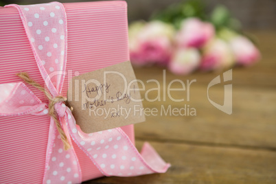Gift box with happy mother day tag on wooden surface