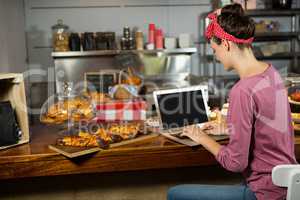 Woman using laptop at bakery counter
