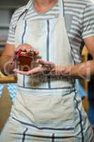 Male shop assistant holding a jar of jam