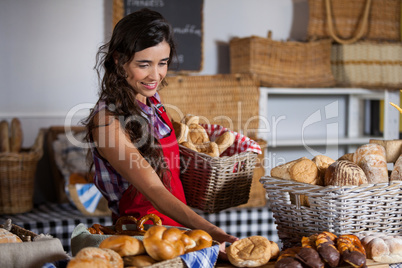 Female staff holding basket of sweet foods in bakery section