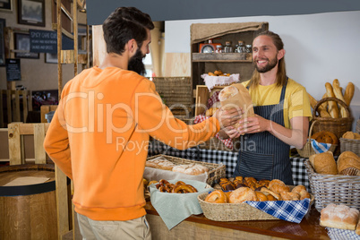 Smiling male customer receiving a parcel from staff at counter