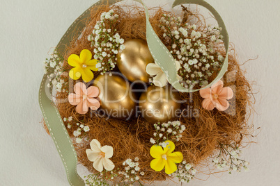 Golden easter eggs with flowers in nest