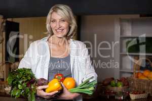 Portrait female costumer holding fresh vegetables and fruits in organic section