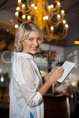 Portrait of female costumer maintain record in notepad
