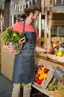Male staff holding leafy vegetable and using digital tablet in organic section