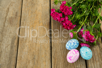 Painted Easter eggs and bunch of flower on wooden background