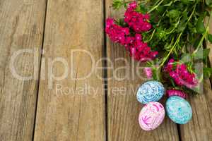 Painted Easter eggs and bunch of flower on wooden background