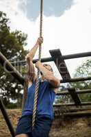 Fit man climbing a rope during obstacle course