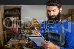 Male staff writing on notepad at counter